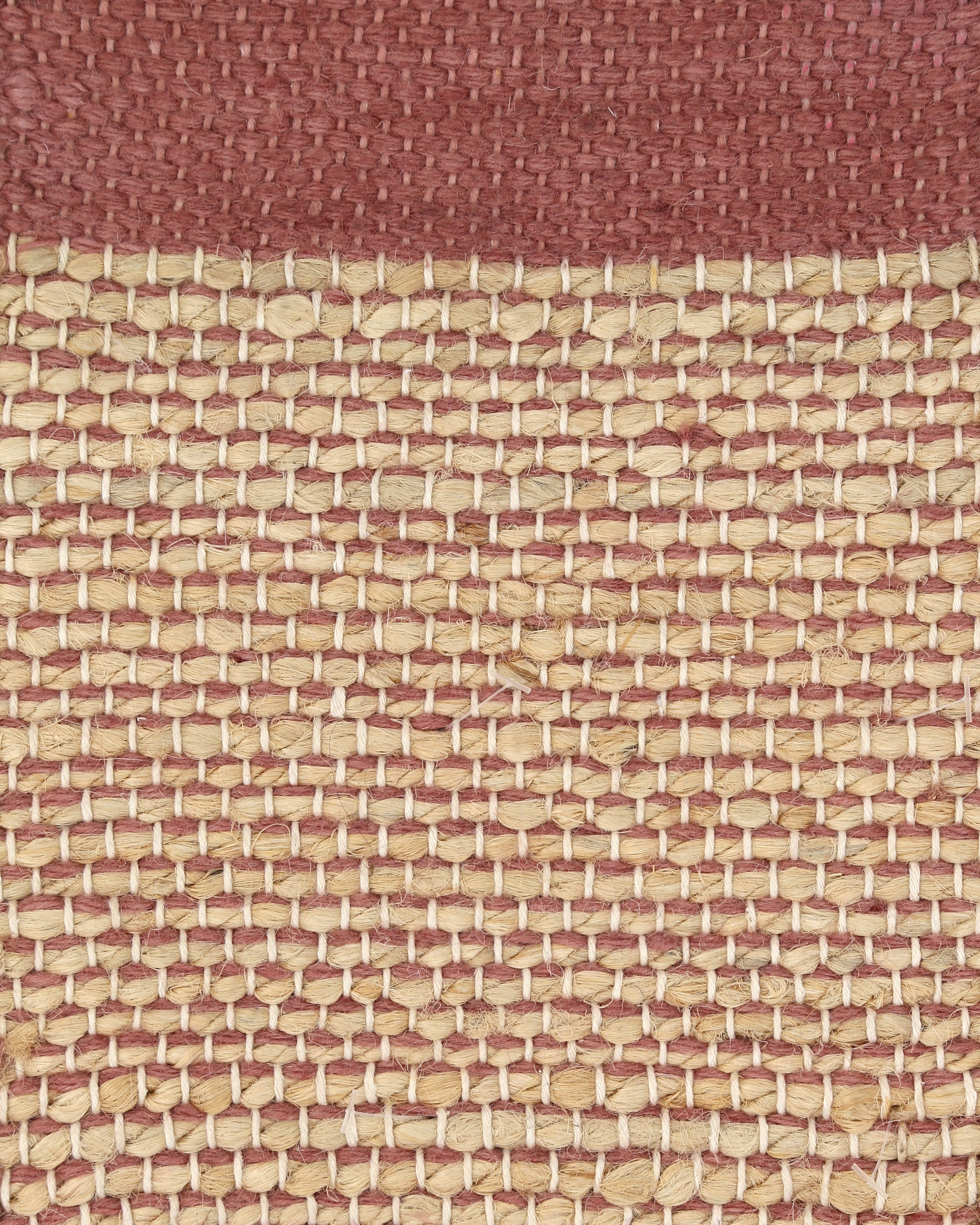 A rectangular Bellagio jute rug with a Vieux Rose (old pink) color border and a plain weave center.