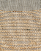 A rectangular jute rug with a solid gray border and a patterned center showcasing a mix of beige and brown tones.