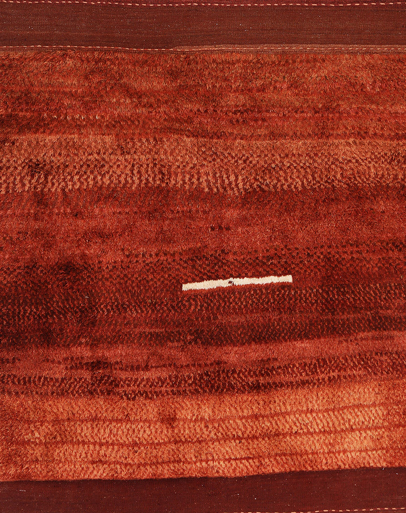 A high pile, rectangular rug with a solid brown color and a textured appearance.