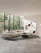 Modern living room with a large sectional sofa, round coffee table, and floor-to-ceiling windows.