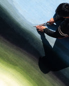 Person using a tool carpet siccors on a textured surface with a gradient background